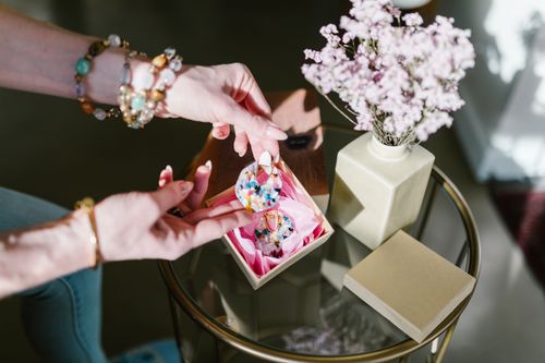 Free Elegant jewelry unboxing experience with floral decor on a glass table, showcasing colorful earrings. Stock Photo