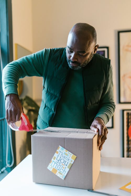 A Man Packing a Cardboard Box with a Thank you Card