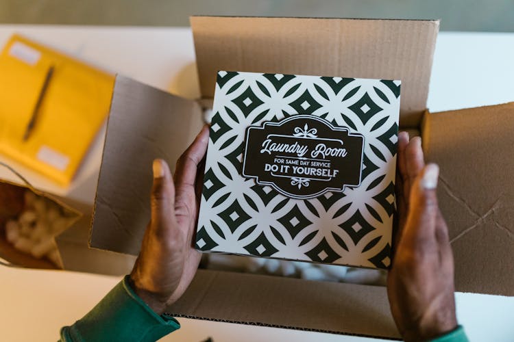 Person Putting A Card On Cardboard Box