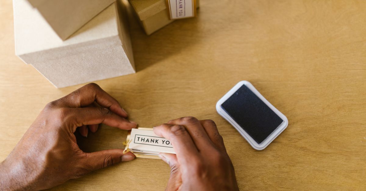 Hands of a small business owner sealing thank you cards with an ink pad.