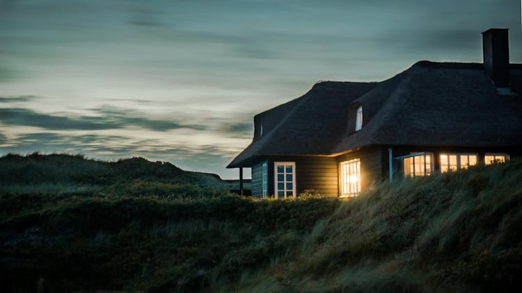 Gray House With Fireplace Surrounded By Grass Under White And Gray Cloudy Sky