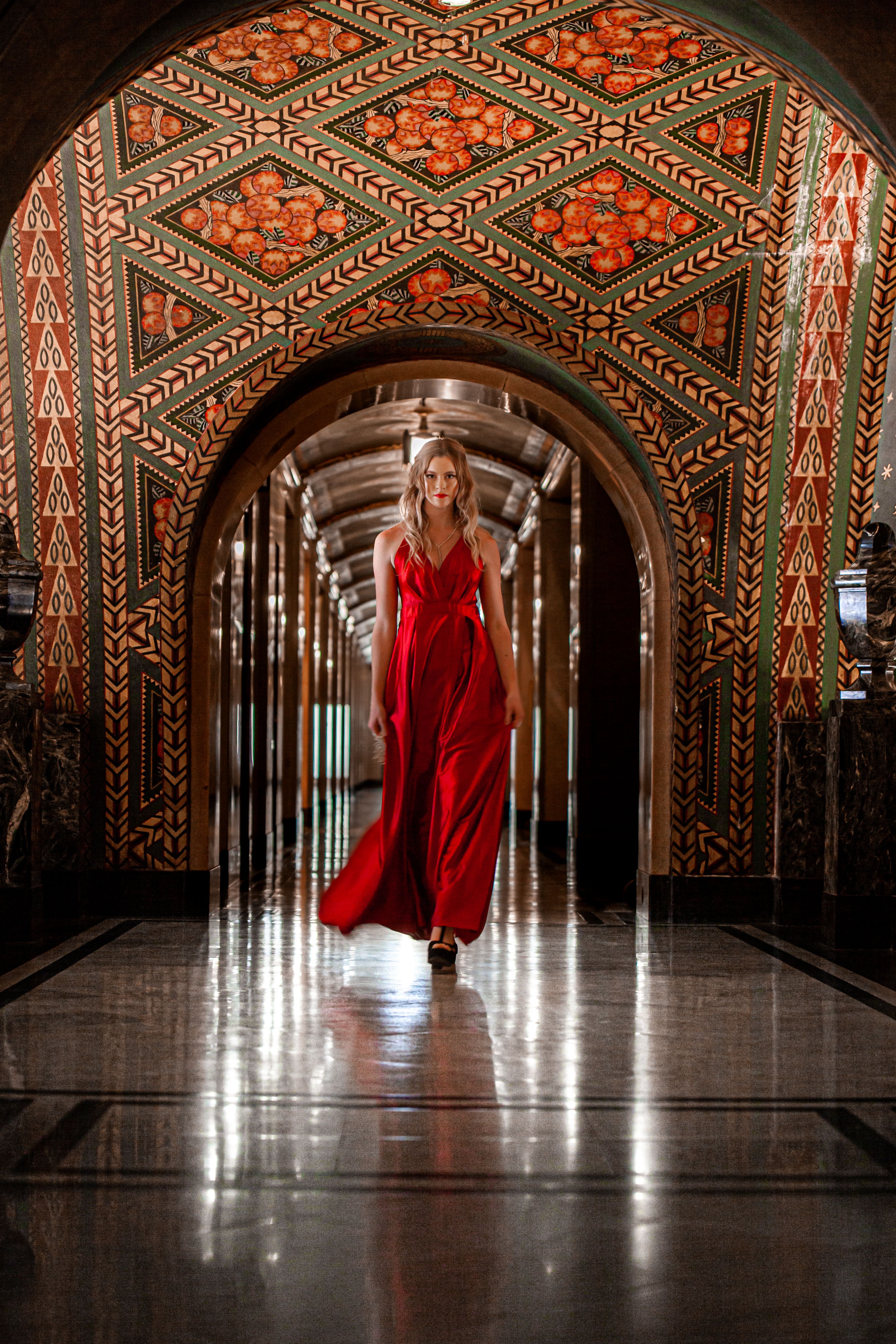 A Woman in Red Dress Walking on an Arched Hallway · Free Stock Photo