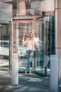 A Woman in White Blazer Standing in a Revolving Glass Door