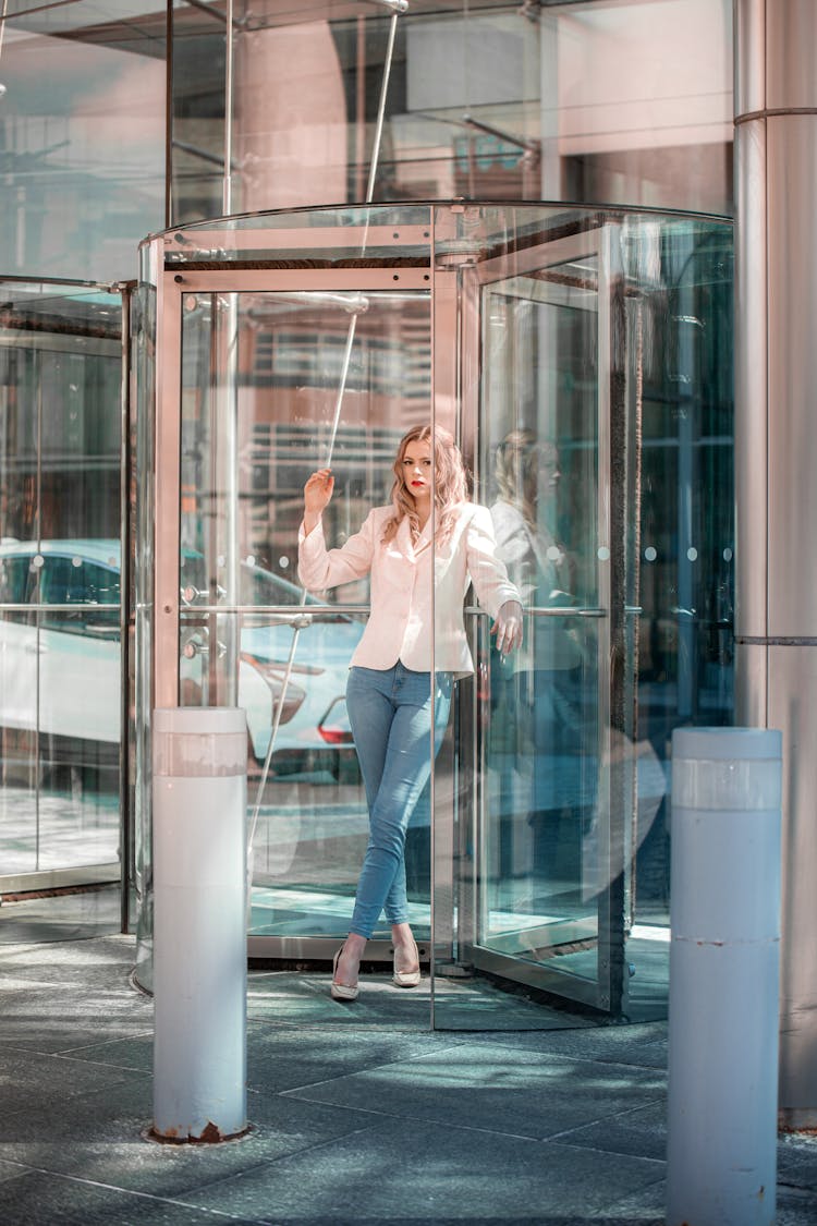 A Woman In White Blazer Standing In A Revolving Glass Door