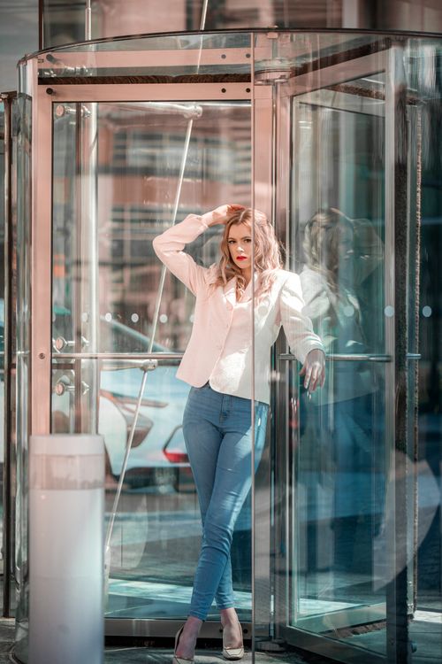 Woman in business casual clothing standing confidently in modern glass entrance