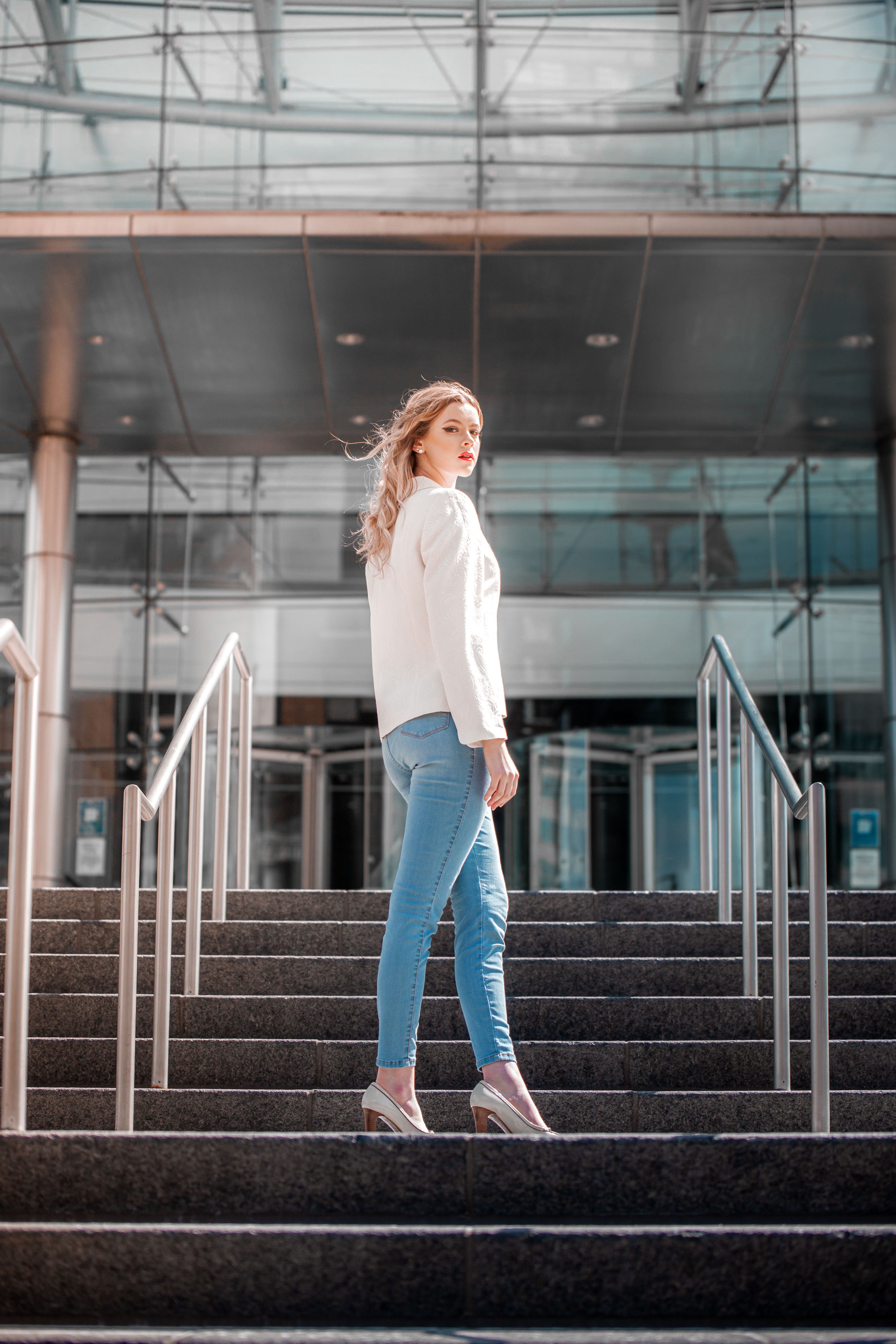 Woman posing on stairs in white blazer and jeans, chic work outfit