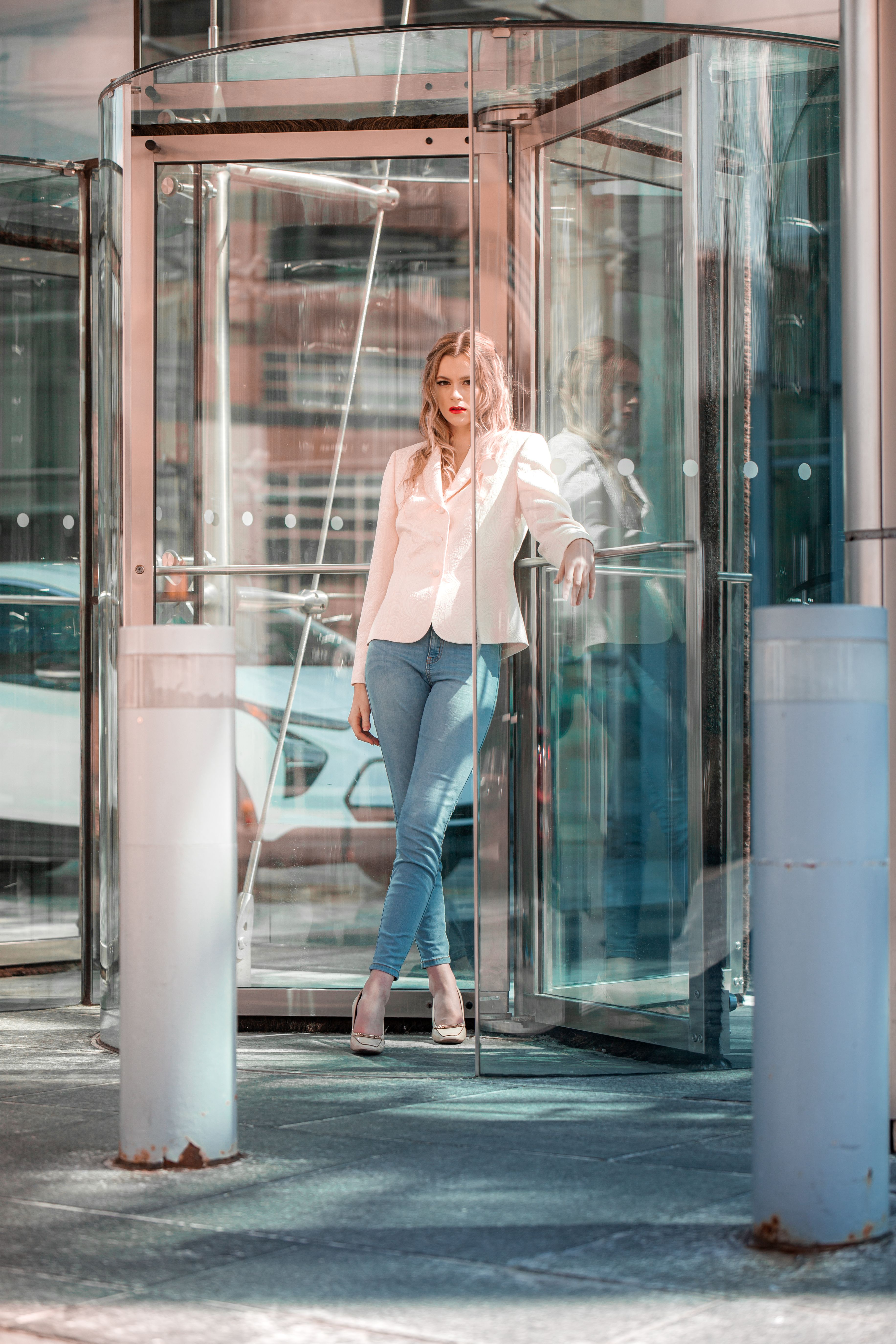 Businesswoman standing confidently in glass revolving door, power office outfit