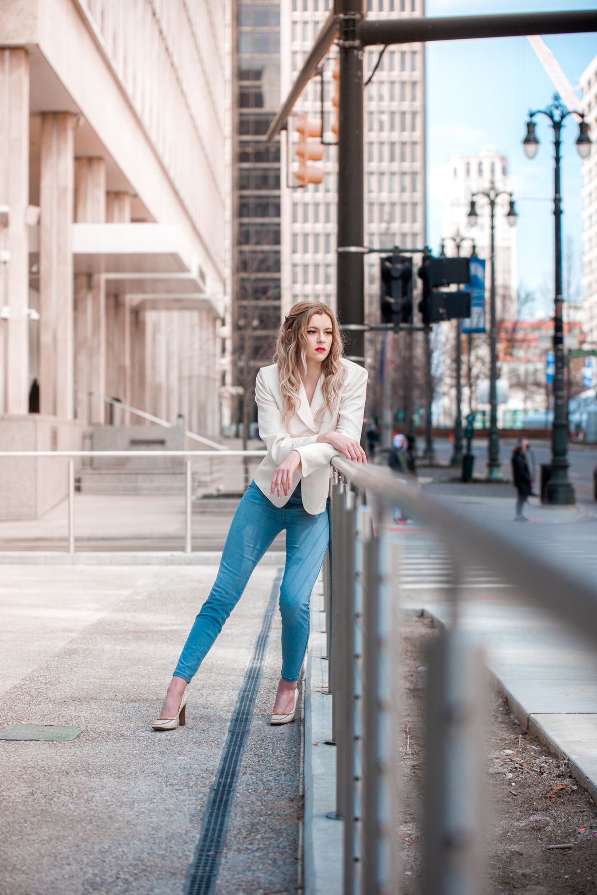 Woman in a white blazer posing in a bright city setting