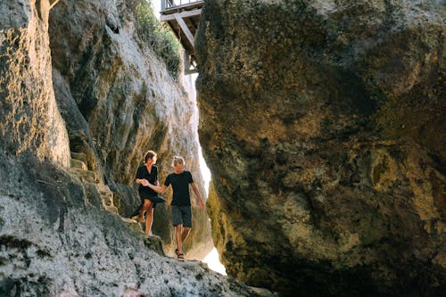 A Couple Holding Hands while Walking on Rock Formations