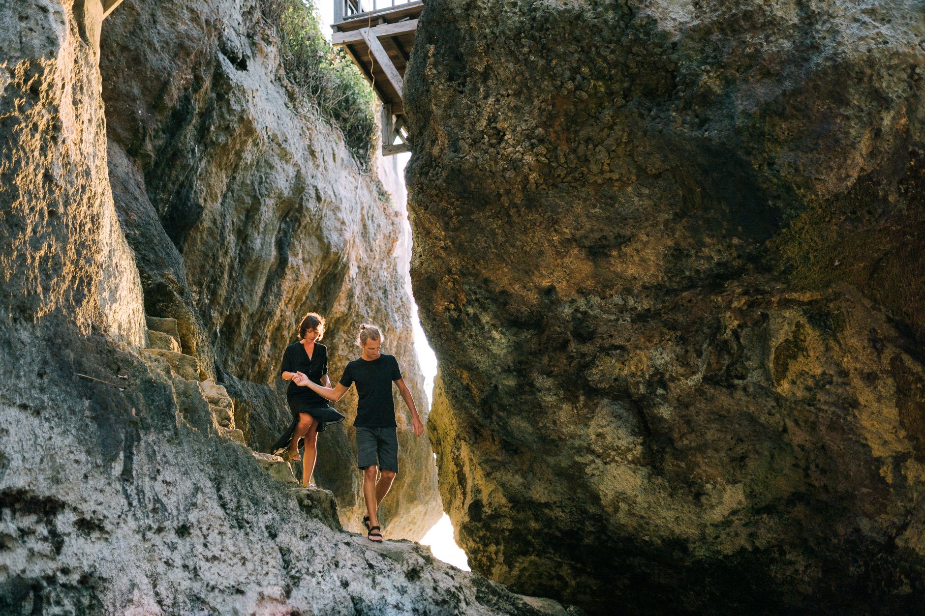 A couple walking hand in hand through rugged rocky terrain, exploring nature together.