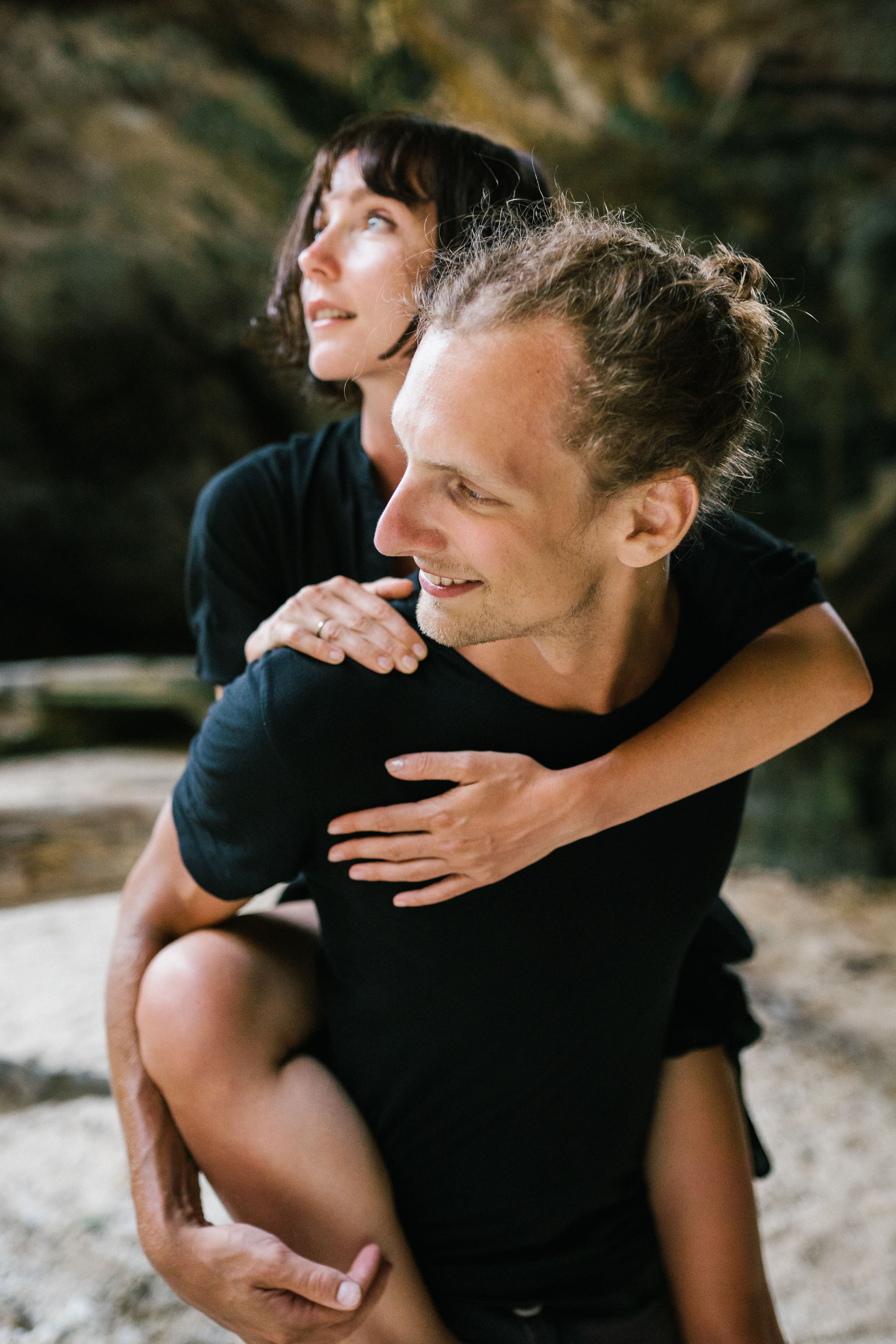 Playful couple joyfully enjoying a piggyback ride outdoors, reflecting love and happiness.