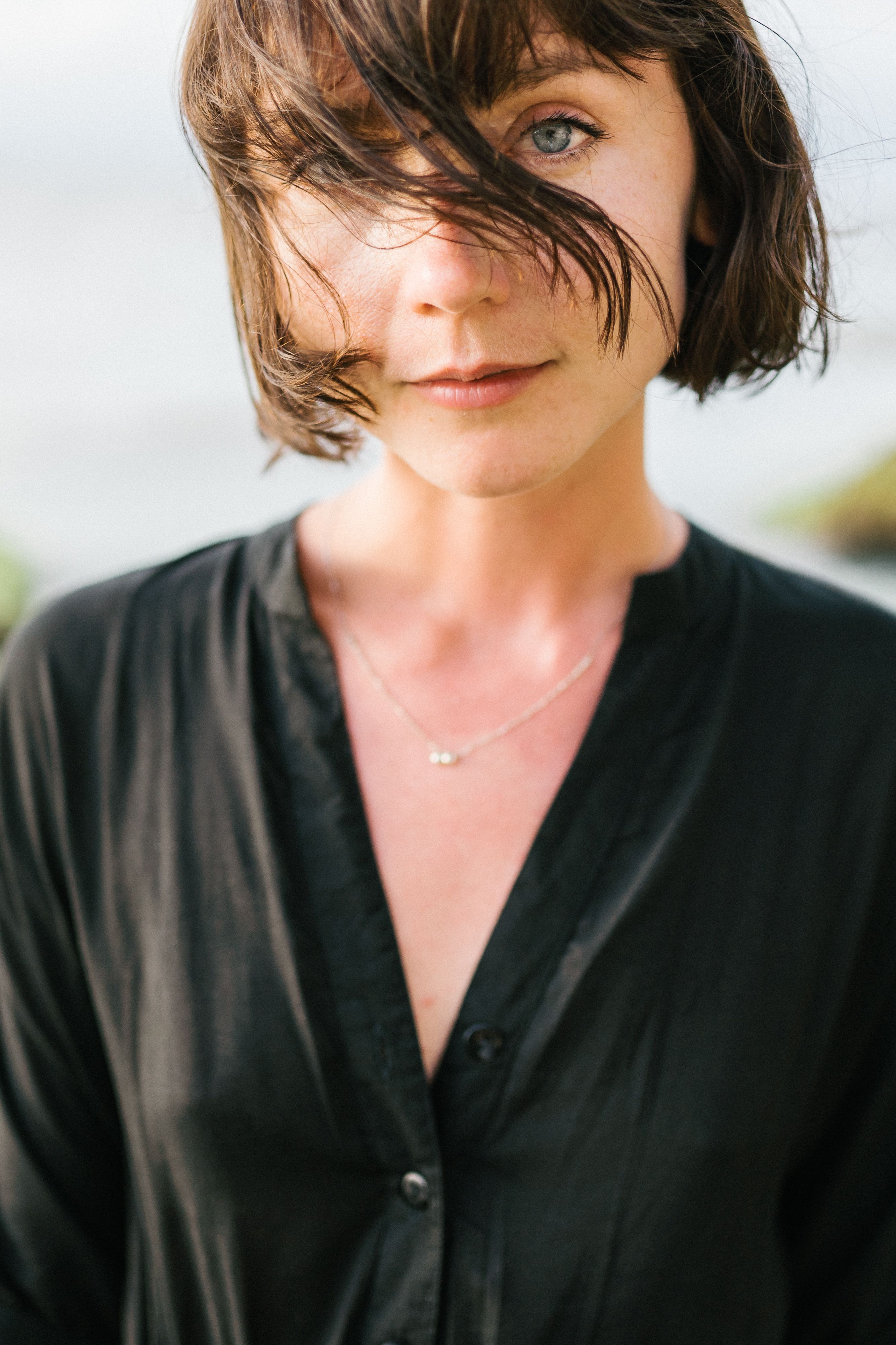 Captivating portrait of a young woman in a black shirt with tousled short hair outdoors.