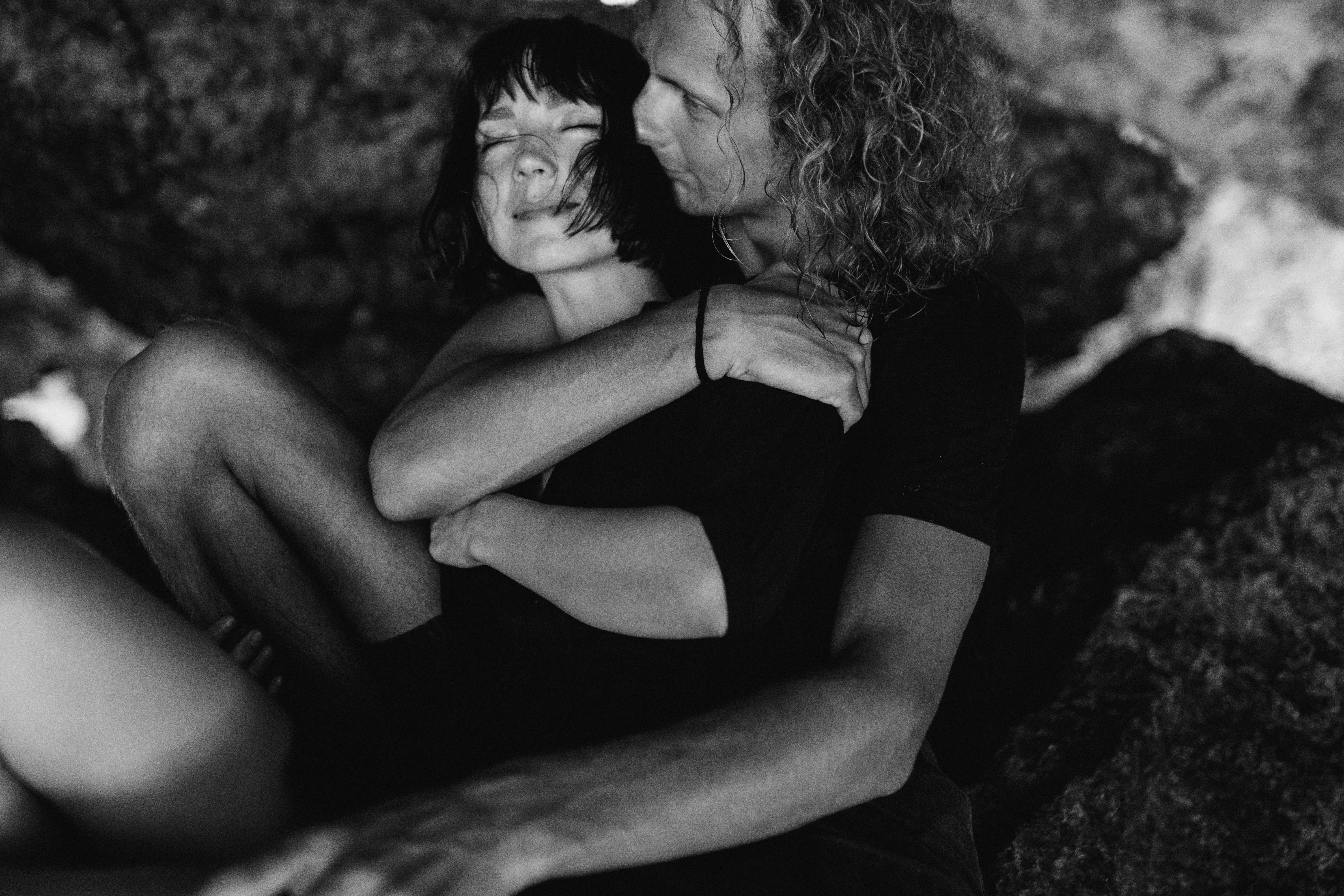 A romantic black and white portrait of a couple embracing in an intimate setting.