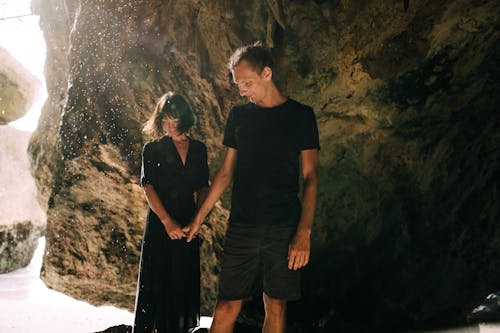 A Couple Holding Each Others Hand while Standing Near Big Rock Formation