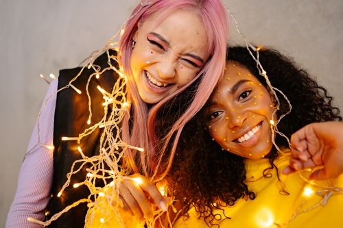 Free Two women enjoying a festive moment with creative makeup and lights. Stock Photo