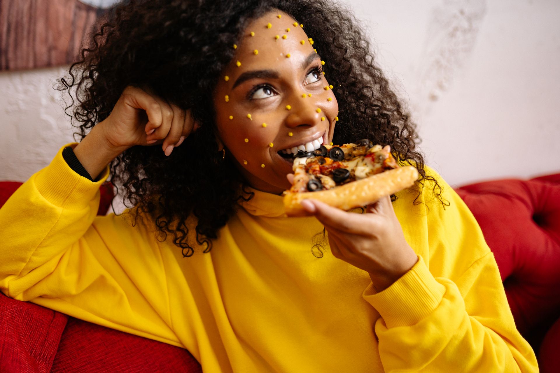 A Woman with Art Make-up on Her Face Eating Pizza