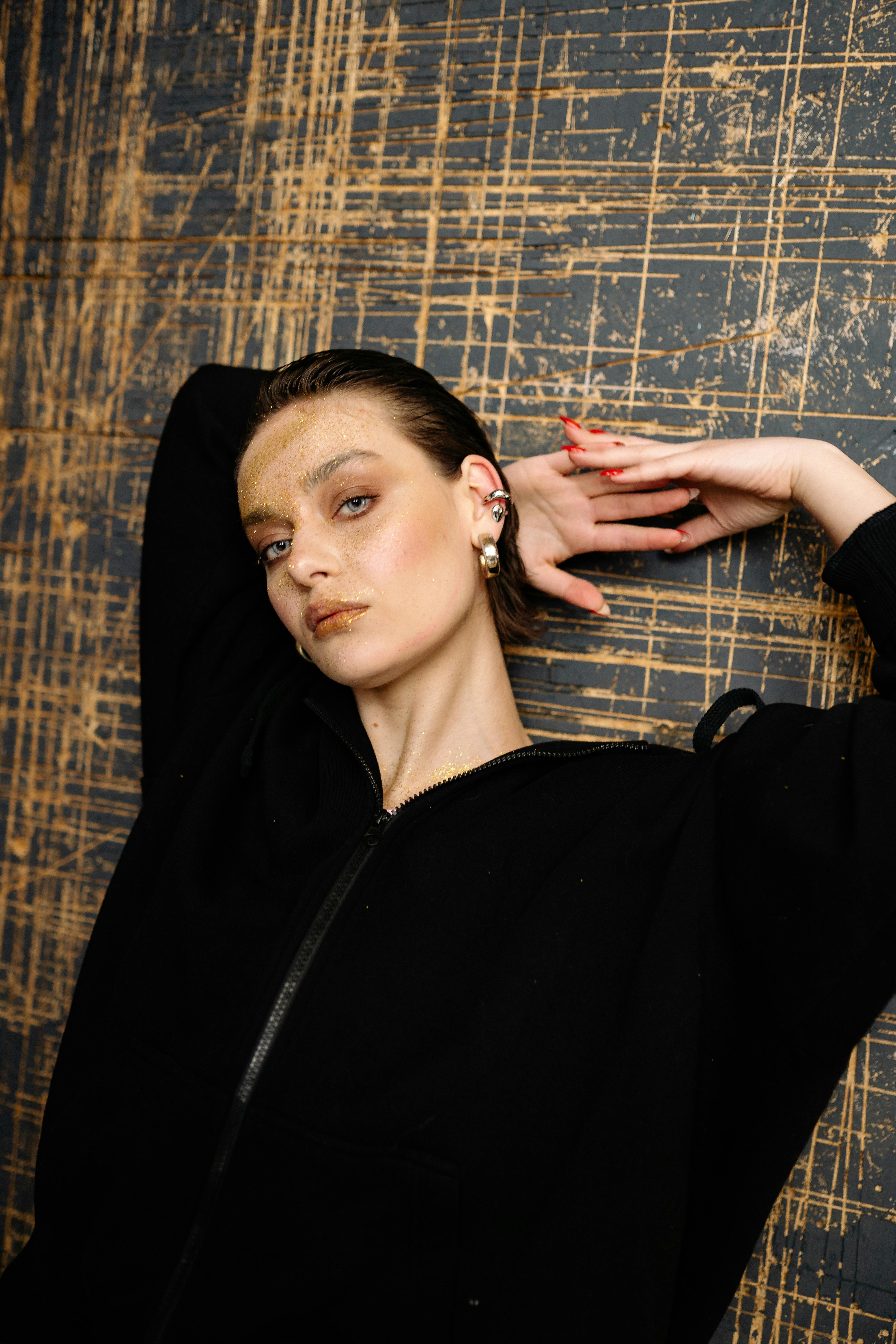 Artistic portrait of a woman posing confidently with unique makeup and earrings.