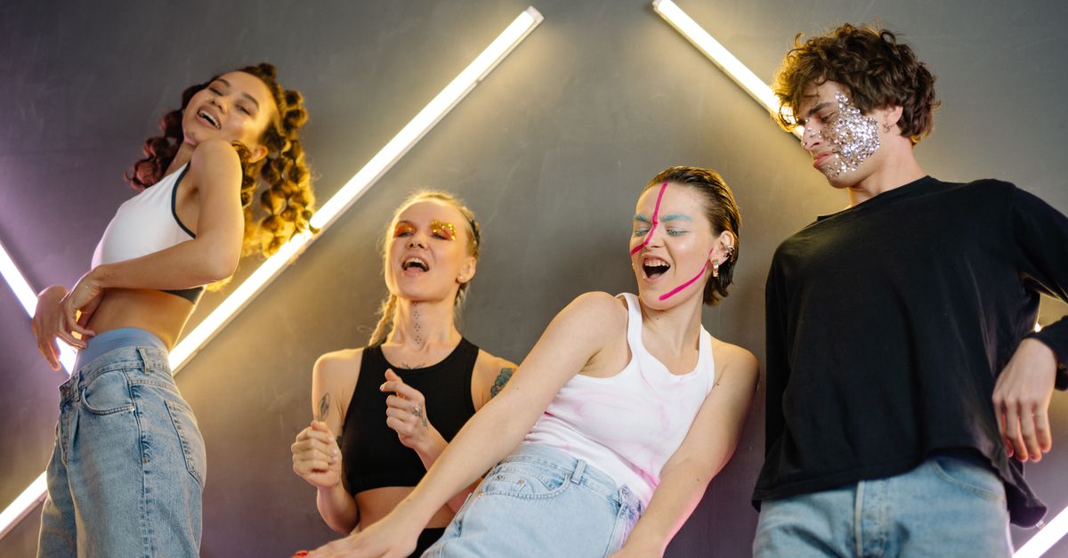 Gen Z teens dancing at a concert with phone screens lit up