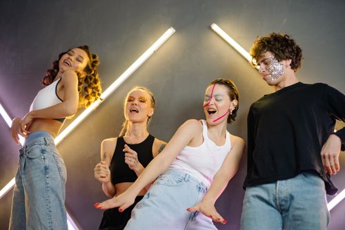 Free A lively group of young adults dancing energetically in a studio with striking neon light decor. Stock Photo