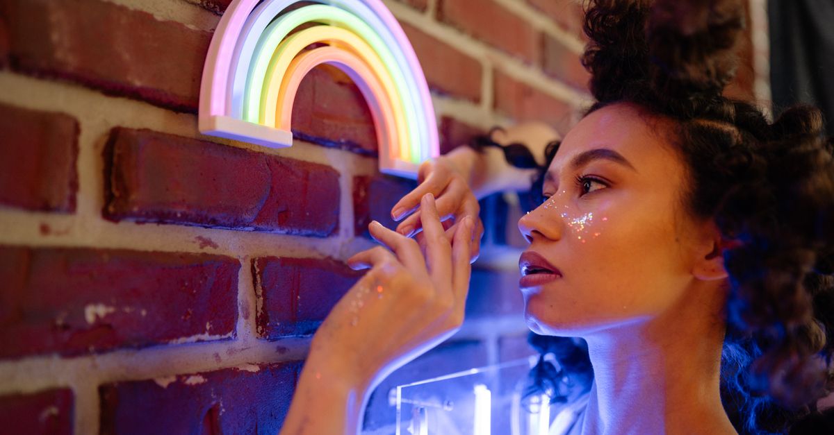 Profile portrait of a young woman with art makeup and neon lights, capturing vibrant colors and creativity.