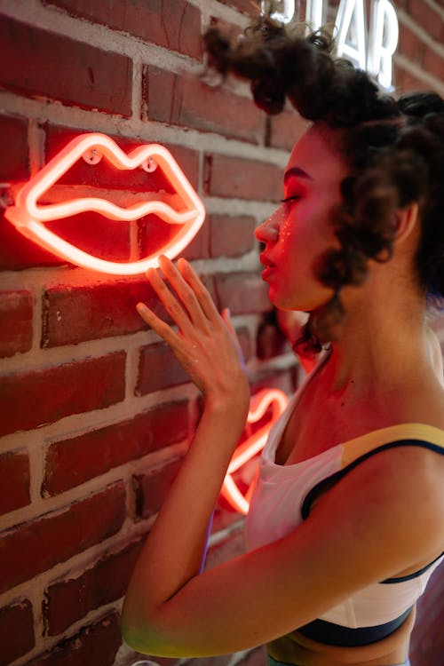 A Young Woman Touching a Lip Shaped Neon Light