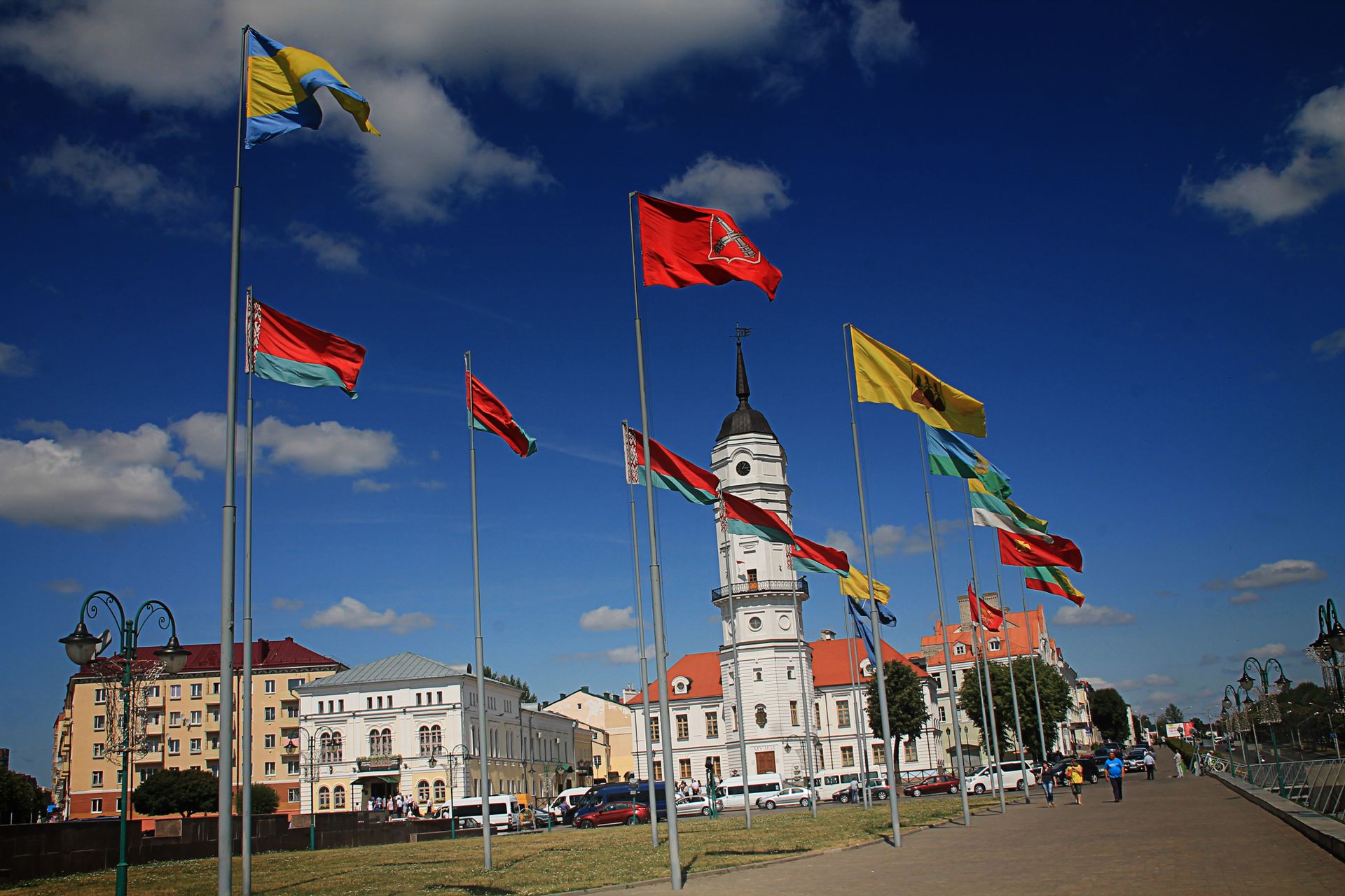 Flags waving near the city hall in Mahilioŭ, Belarus against a deep blue sky.