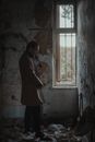 Man in Brown Coat Standing Inside a Room of an Abandoned Building