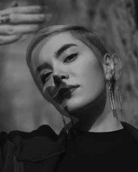 Striking black and white portrait of a woman with short hair and bold earrings, capturing elegance and mystery.