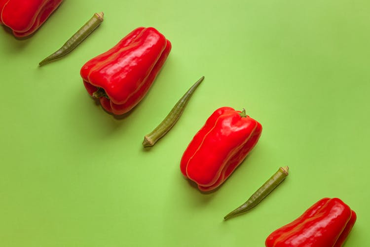 Close-Up Shot Of Red Peppers And Okra On A Green Surface