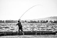 一个人在海边钓鱼，背景是城市风景