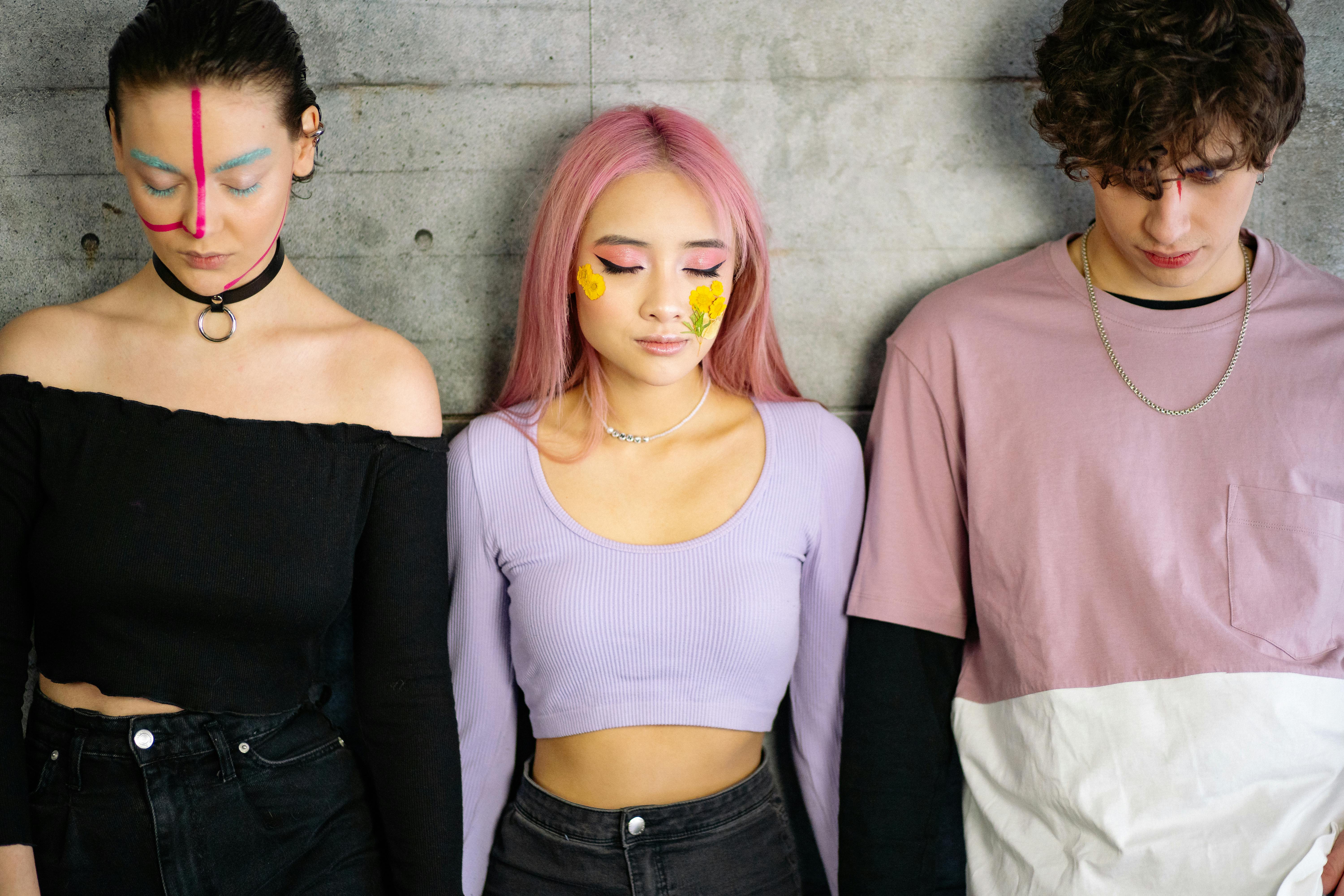 three people leaning with face paint leaning on concrete wall