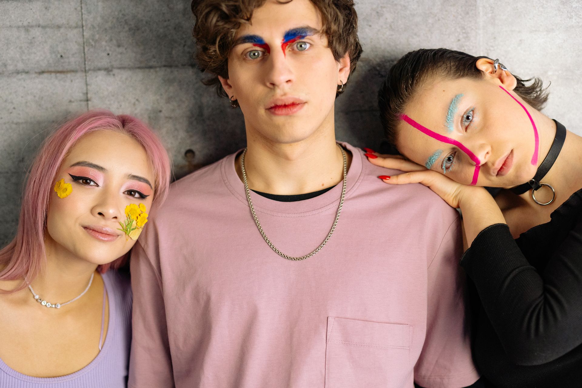 A striking portrait of three people with colorful and artistic makeup, showcasing creativity and bold styles.