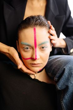 Close-up portrait of a woman with vibrant art makeup and striking expression.