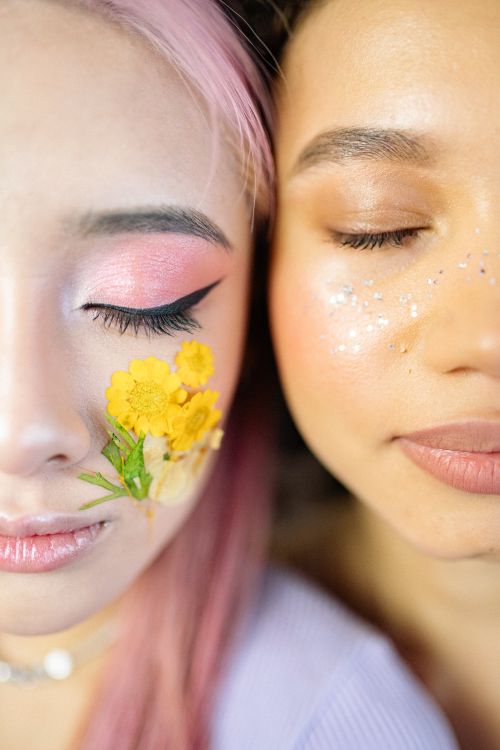 Free Artistic close-up of two young women with glitter and floral makeup, eyes closed. Stock Photo