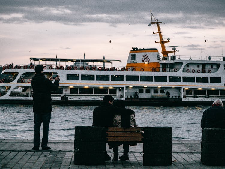 People On A Pier And A Big Cruise Ship In Front Of Them 