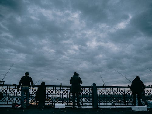 People Fishing on the Galata Bridge Under Dark Cloudy Sky