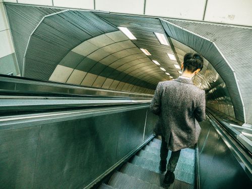 Free Man in gray coat descending an escalator in a modern Istanbul subway tunnel. Stock Photo