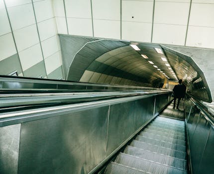A man descends a sleek, modern escalator within a subway tunnel in Istanbul, Turkey.