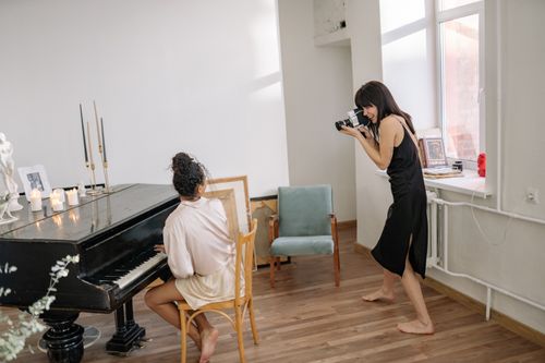 Free Woman photographing a pianist in a cozy, light-filled room, creating a warm, artistic vibe. Stock Photo