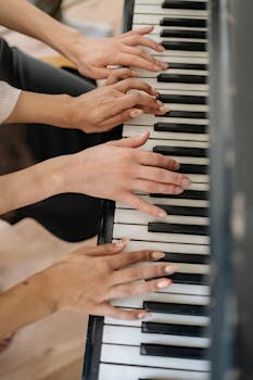 Close-up of multiple hands playing a piano, showcasing collaboration in music.