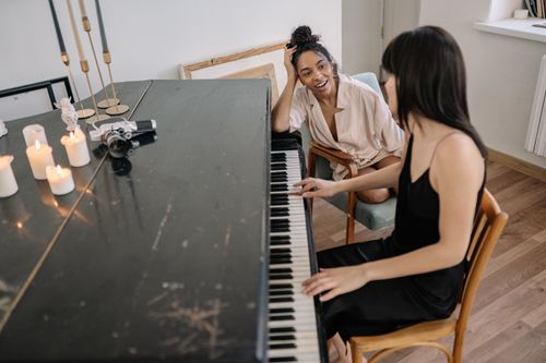 Free Intimate moment of a lesbian couple at home with piano and candles, exuding warmth and togetherness. Stock Photo