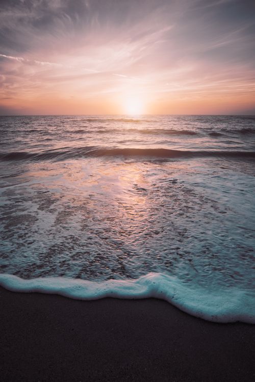 Free Captivating sunrise over the ocean at Melbourne Beach with waves gently crashing on the shore. Stock Photo