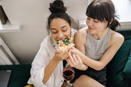 Women Sitting on the Couch While Eating Pizza