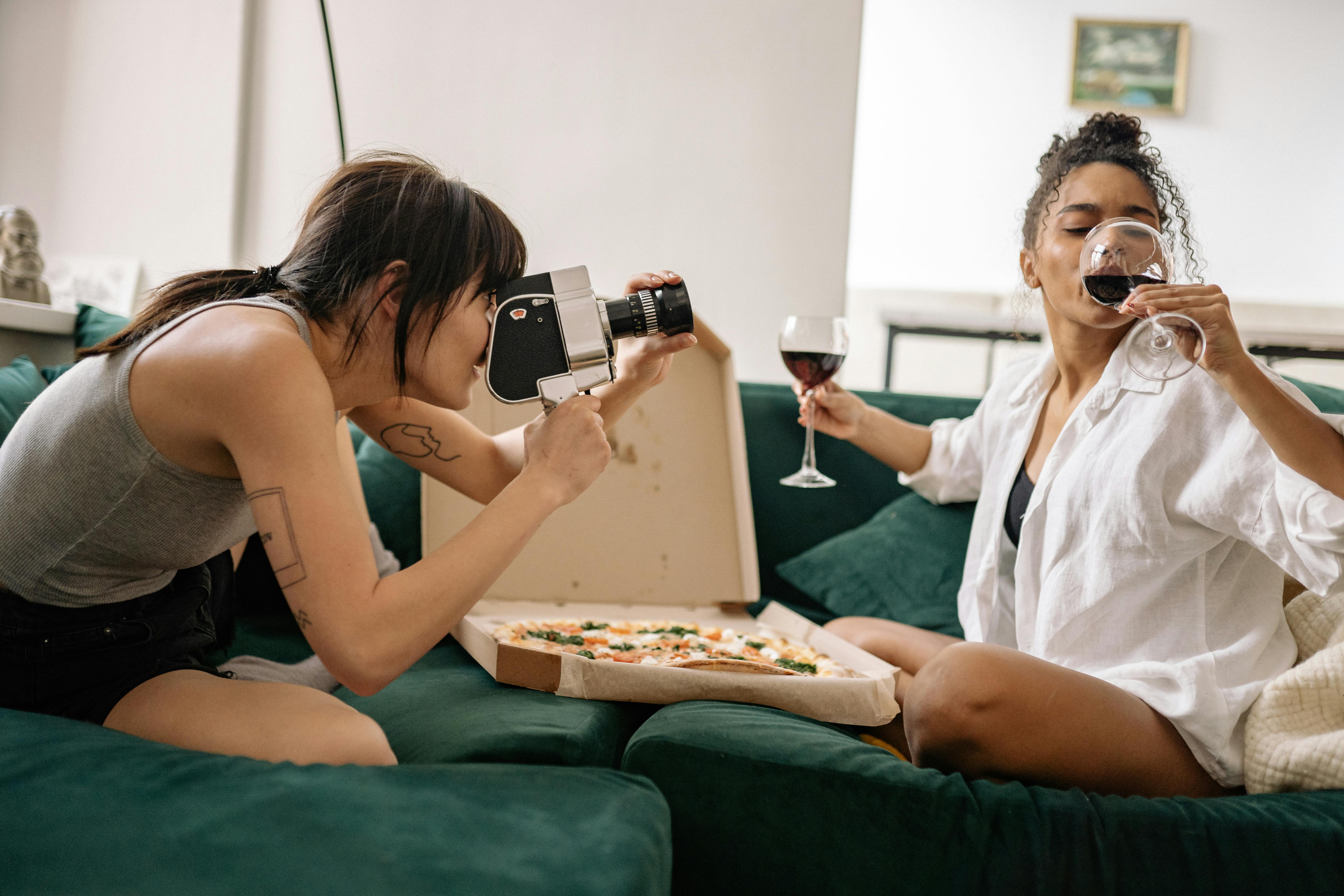 two women sitting on green couch with pizza