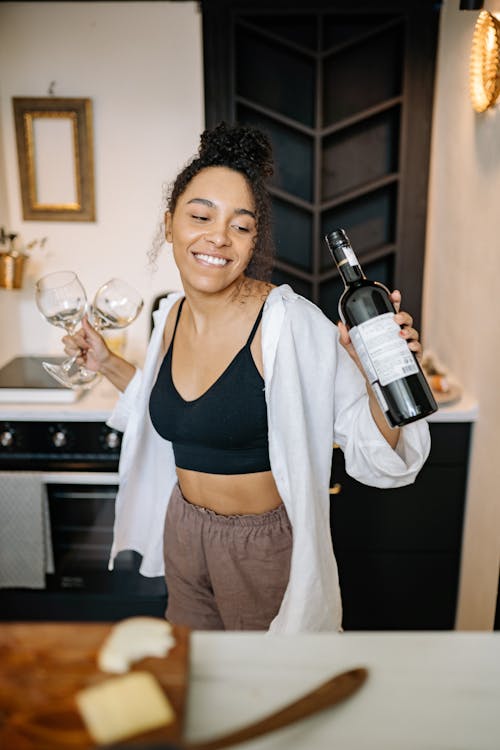 Photo of a Woman Smiling while Holding a Bottle of Wine