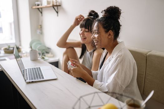 Happy women playing video games on a laptop in a cozy indoor setting.
