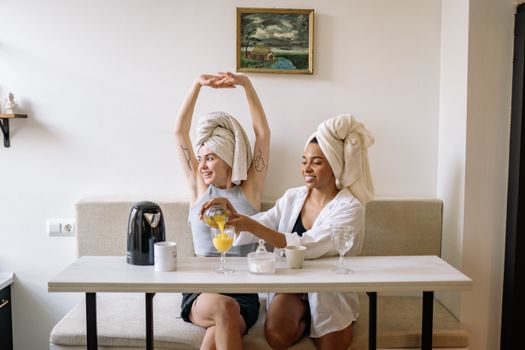 Two women enjoying a cozy morning indoors, sharing juice and conversation.
