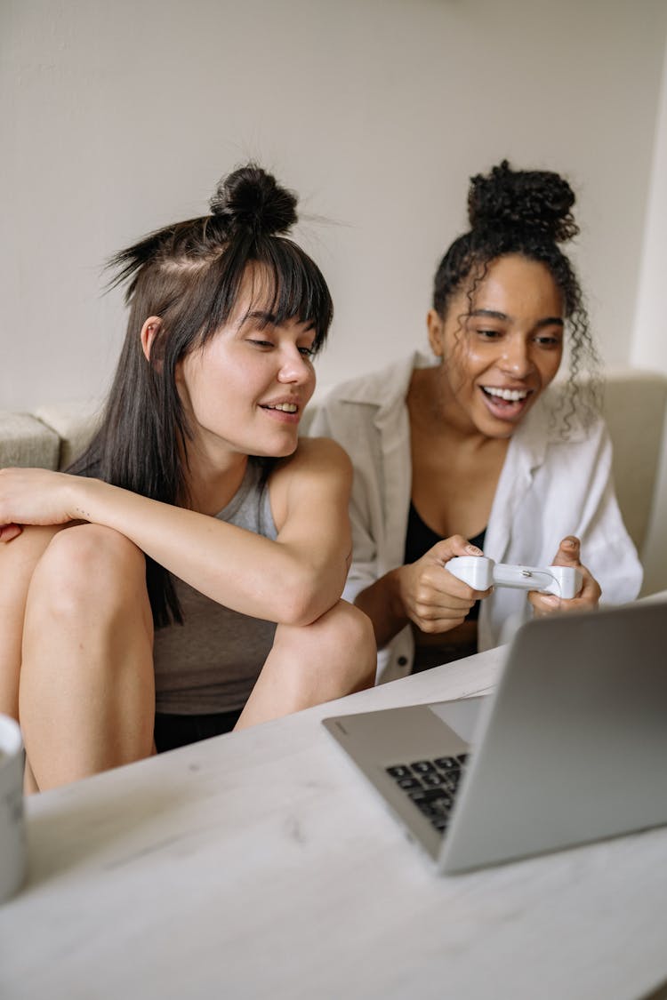 A Woman Sitting Beside A Woman Playing Computer Game