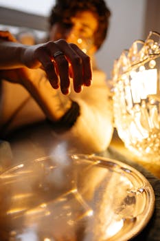 Artistic shot of a hand reaching towards warm, glowing lights with moody lighting.