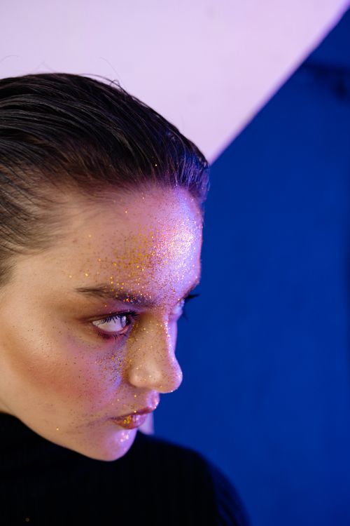 Free Close-up portrait of a woman with glitter makeup against colorful geometric background. Stock Photo